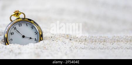 A vintage gold old watch in the sand in daylight. Stock Photo