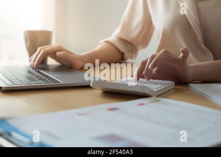 Close up hand of woman using computer calculating household finances or taxes on machine, female manage home family expenditures, using calculator Stock Photo