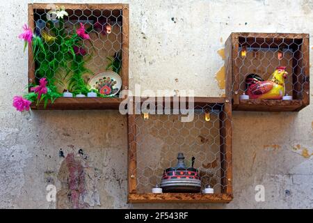 Still life of three wooden boxes, artificial flowers and dishes hanging on the wall. Stock Photo