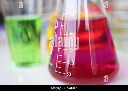 Glass flasks with colored liquids standing on table in chemical laboratory closeup Stock Photo