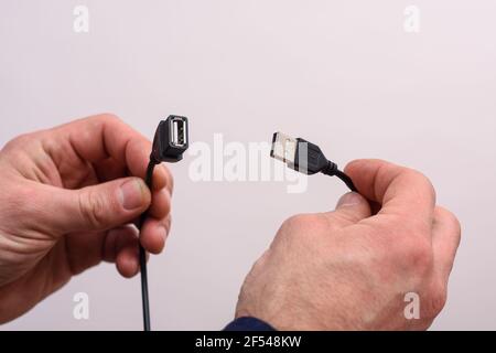 Black USB extension cord in the hands of a man on a white background. Stock Photo