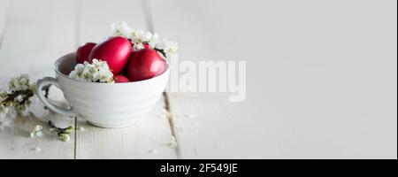 Red Easter eggs with spring blossoms, natural painted festive Easter eggs with white spring flowers and buds composition, Easter holidays Stock Photo