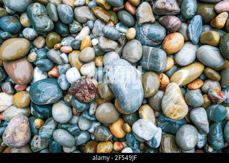 Colored stones on the beach soaked by the textura water. Stock Photo