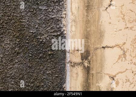 Rough wall texture of 2 sections: uneven dark gray and weathered beige-painted surface Stock Photo