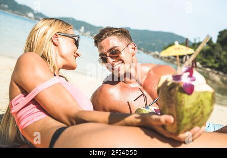 Portrait of young couple vacationer having fun on tropical Phuket beach in Thailand with coconut drink - Active youth and travel concept Stock Photo