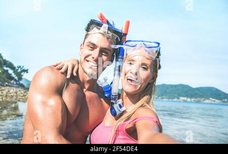 Young happy couple in love taking selfie in tropical excursion with water camera - Boat trip snorkeling in exotic scenarios - Youth lifestyle concept Stock Photo