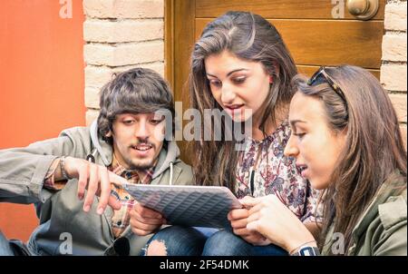 Happy friends having fun with modern digital tablet - Young students studying together outdoors with electronic device - University free time concept Stock Photo