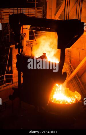 Metallurgical bucket in silhouette with liquid hot metal. Metal alloy plant. Stock Photo