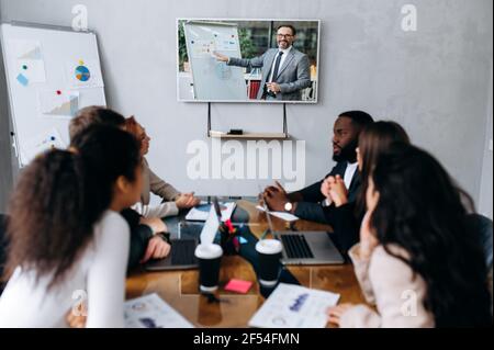 Multiracial group of business people talking about new strategy for company, having a brainstorm, online briefing with director. Successful coworkers discussing ideas and plans, partnership concept Stock Photo