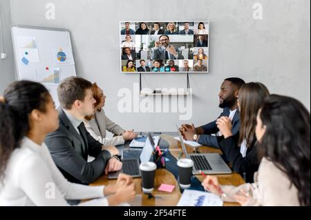 Concept of successful negotiations and team work. Young adult multiracial colleagues discussing ideas for new business plan, talking about work process during online business meeting with colleagues Stock Photo