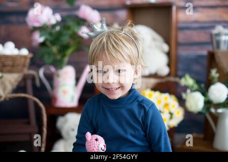 Beaufitlu toddler blond boy, wearing little crown, pretending to be prince, child playing imaginary games Stock Photo