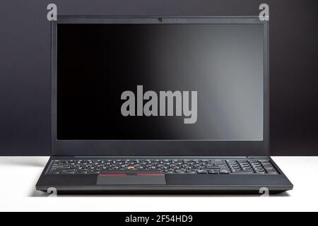 Empty open laptop with mockup on white desk table with black screen. minimalist work space with modern notebook. Personal laptop screen template for Stock Photo