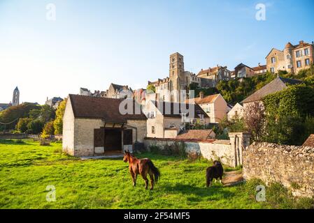 View of medieval city of Chateau-Landon and grazing horses. Seine-et-Marne department of Ile-de-France region, France. Rural tourism background Stock Photo