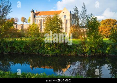 Ancient Saint Severin abbey building (nowadays nursing home) and its reflection in water. Chateau-Landon, France. Autumn travel in French countryside. Stock Photo