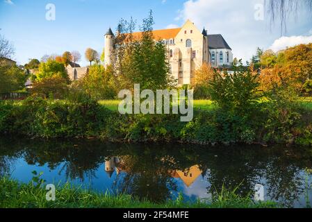 Ancient Saint Severin abbey building (nowadays nursing home) and its reflection in water. Chateau-Landon, France. Autumn travel in French countryside. Stock Photo