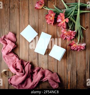 Bouquet of beautiful tulips and white boxes on a wooden table. curly tulip. Lightweight pink scarf Stock Photo