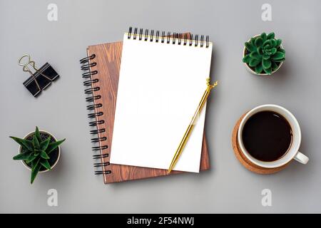 open notepad, cup of coffee, succulents, golden pen on gray background, spiral notebook on table Business, planning, education, morning life working f Stock Photo
