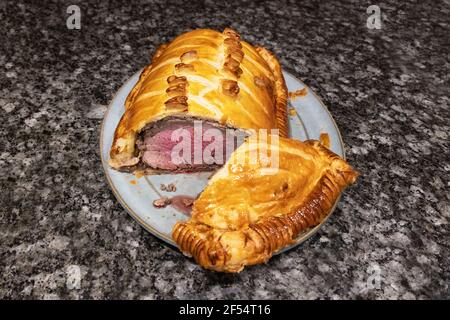 Beef Wellington, cut to show rare cooked fillet beef layered with chestnut mushrooms, parma ham and puff pastry (beef en croute); and oven cooked; UK Stock Photo