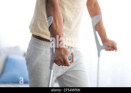 Cropped view of young black guy using crutches, having leg injury or broken bone at home Stock Photo