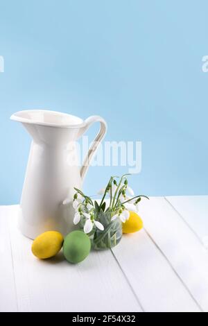 Background wit fresh snowdrops in a glass vase and easter eggs Stock Photo