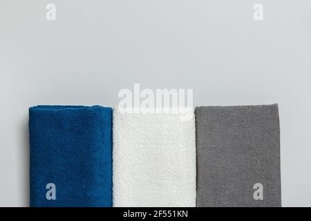 Close-up on three terry towels of blue, white and gray colors. Flat lay top view with copy space. Stock Photo