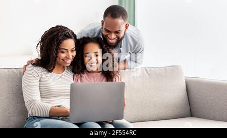 Happy african american family using laptop in living room Stock Photo