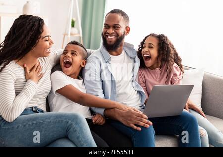Laughing african american family using laptop in living room Stock Photo
