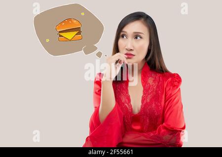 A woman want to eat hamburgers during the night. When a woman in a red satin nightgown and lace robe wake up hungry late at night. Food cravings Stock Photo