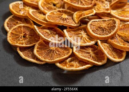 Slices of dehydrated orange on black stone. Selective focus. Stock Photo