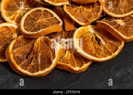 Slices of dehydrated orange on black stone. Selective focus. Stock Photo