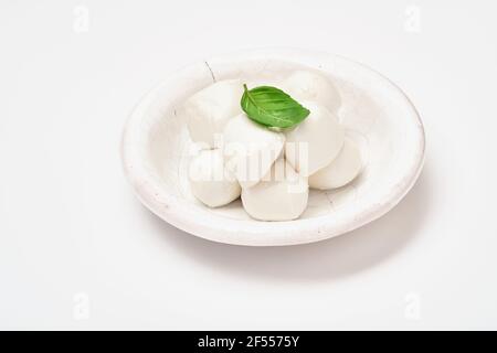 Baby mozzarella cheese with basil leaf in white ceramic plate isolated on white background. Group of bocconcini mozzarella. Stock Photo