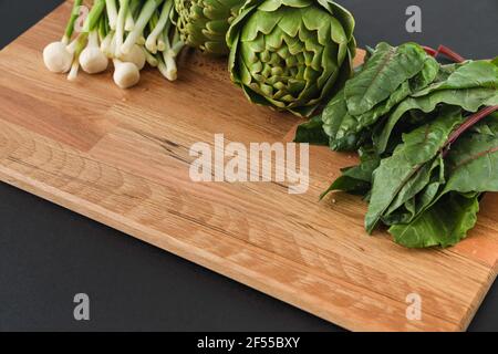 Selective Focus of variety raw green vegetables salads, green artichoke, savoy cabbage, green onion and cherry tomatoes as frame over wooden texture. Stock Photo