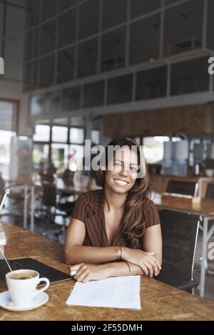 Vertical shot charming female entrepreneur sit meeting co-working cafe smiling pleasantly look camera communicating applicants during interview Stock Photo