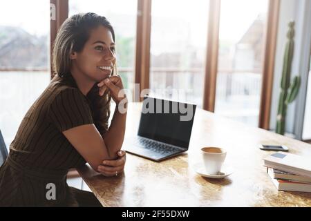 Good-looking successful ambitious female entrepreneur sit cafe co-working space turn aside smiling pleased laughing talking coworkers prepare project Stock Photo
