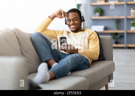 Happy black guy watching videos on mobile phone Stock Photo