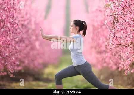Side view portrait of a woman doing tai chi exercise in a pink flowered field Stock Photo