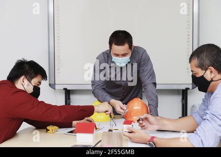 Confident team of architect working together in a office. They discussing about new startup project on desk. Architect discuss with engineer about pro Stock Photo