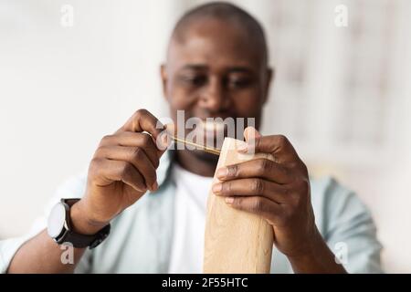 Carpentry and furniture assembly. African american man assembling wooden table with details, using bolt Stock Photo