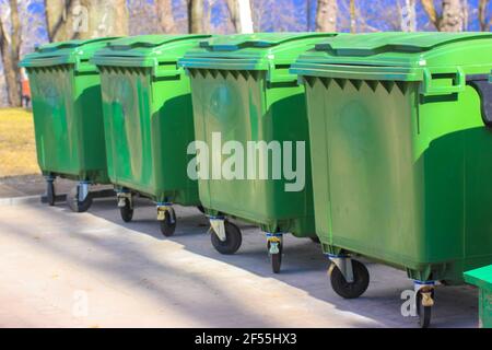 Large green plastic trash cans on city street. Containers on wheels with a  handle to collect commercial and resident trash. Disposal of household and  Stock Photo - Alamy