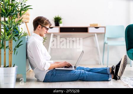 Handsome young man using laptop in living room Stock Photo