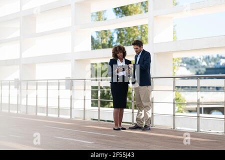 Business team working on digital tablet while standing by railing Stock Photo