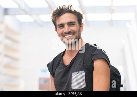 Mid adult man with backpack smiling while standing outdoors Stock Photo