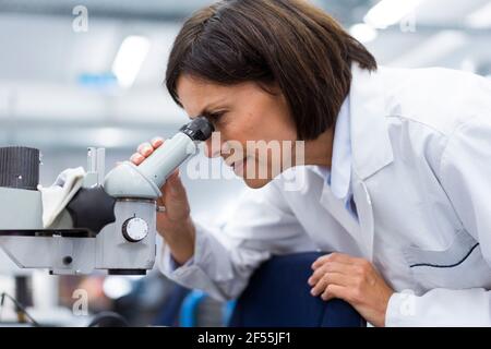 Female scientist using microscope while working in laboratory Stock Photo