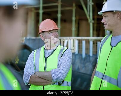 Two male construction workers talking outdoors Stock Photo