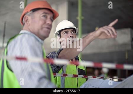Two male construction workers talking at construction site Stock Photo