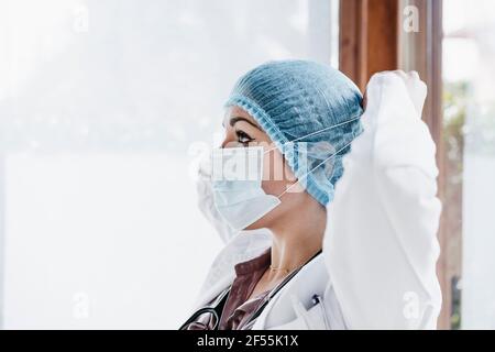 Female doctor in surgical cap wearing protective face mask Stock Photo