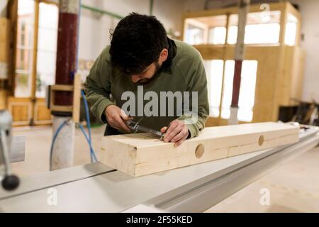 Male carpenter measuring wood with vernier calliper in workshop Stock Photo