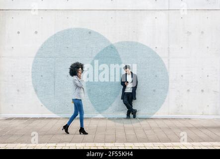 Graphic visualization of data exchanged by man and woman using smart phones outdoors Stock Photo