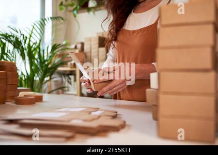 Woman packing soap in brown boxes at workshop Stock Photo