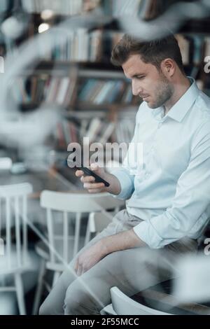 Businessman using mobile phone while sitting at cafe Stock Photo